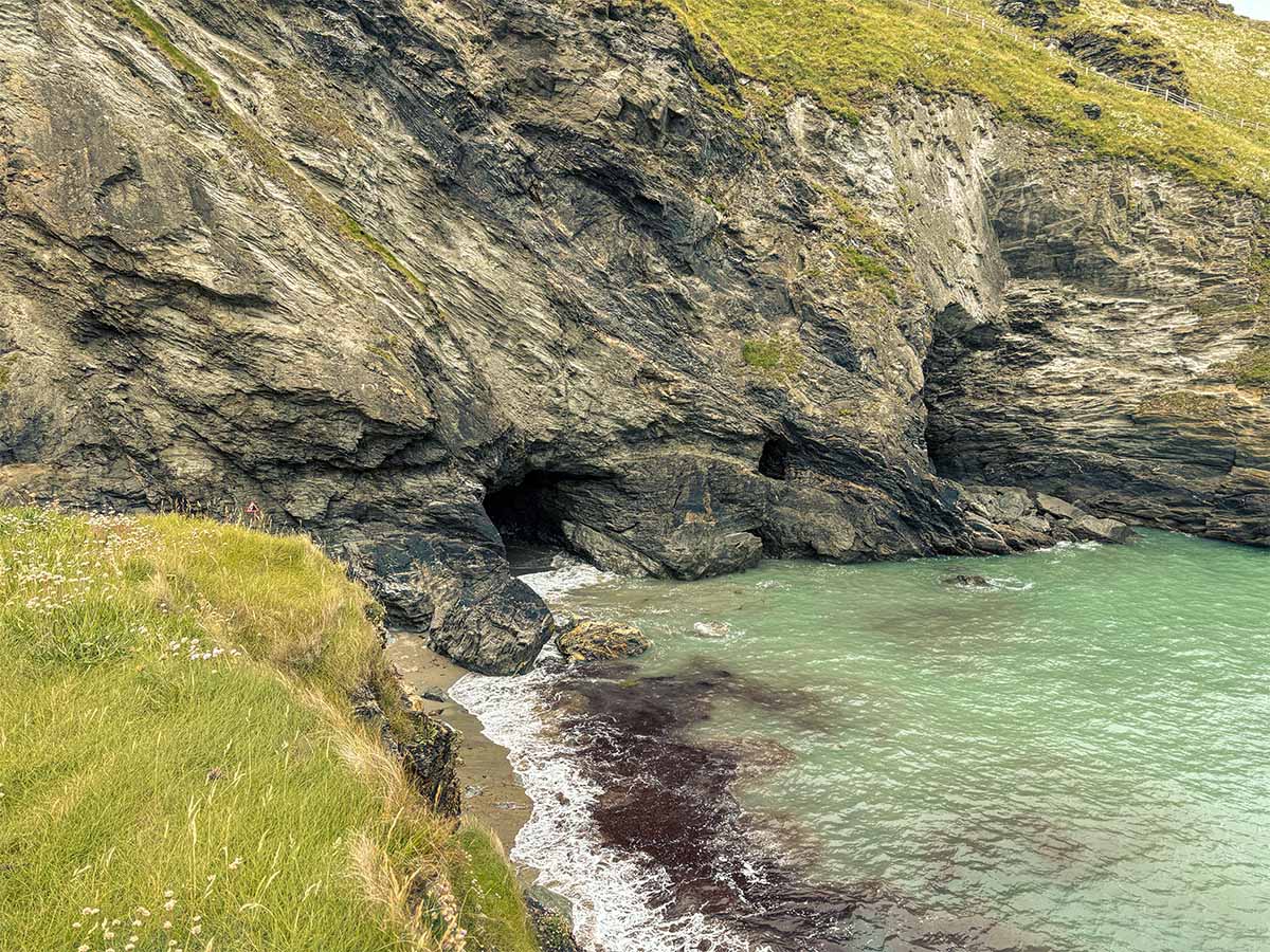 Spiaggia rocciosa e ingresso della Grotta di Merlino a Tintagel durante la bassa marea